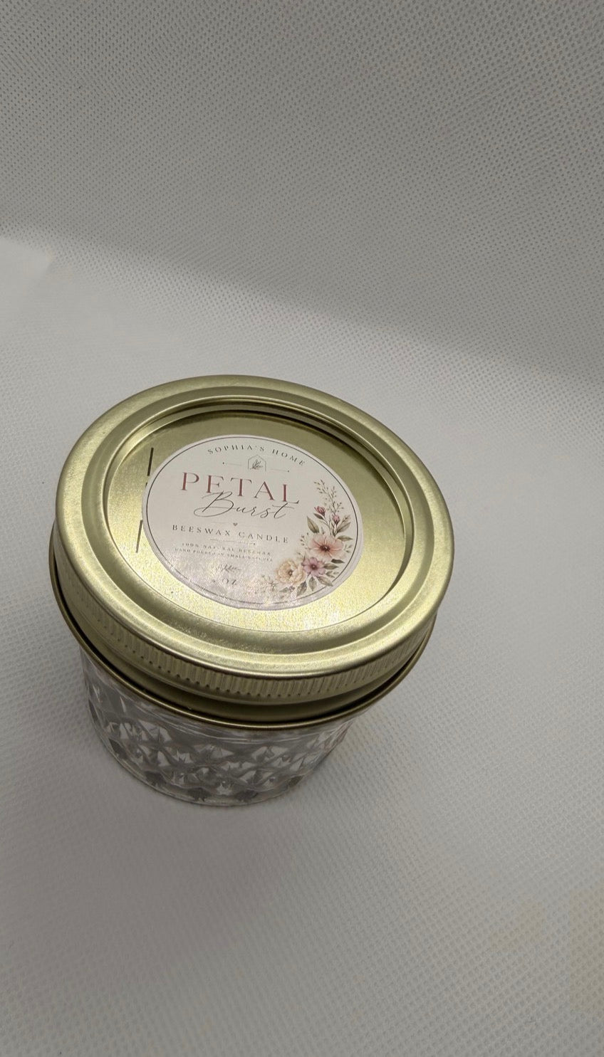 Petal Burst candle in a textured glass jar with a gold-tone lid and floral label
